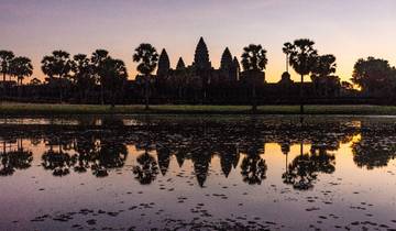 Angkor Wat silhouette reflected in water at sunrise.