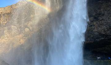 Waterfall with rainbow and onlookers below.