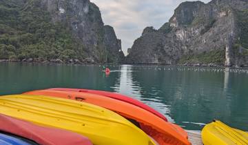 Colorful kayaks lined up with scenic cliffs over the water.