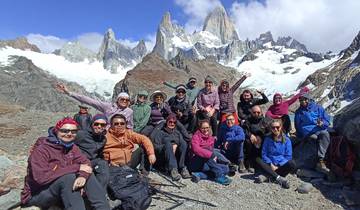 Group of trekkers posing in front of snow-capped mountains.
