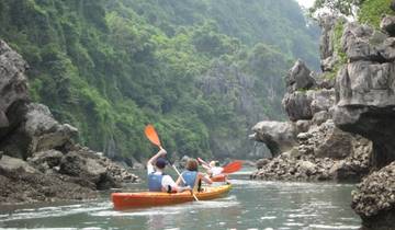 People kayaking through narrow rocky passageway.