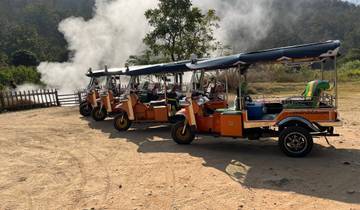 Row of tuk-tuks parked with steam rising in the background.