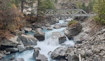 Mountain stream flowing under a bridge with rocky banks.