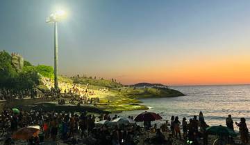 Crowded beach at sunset, people enjoying the view.