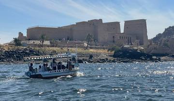 A small boat on a river with a temple-like structure in the background.