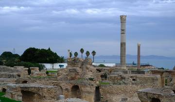 Overlooking ancient ruins by the sea with surviving stone pillars.