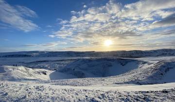 Snowy landscape with sun low on the horizon casting long shadows.