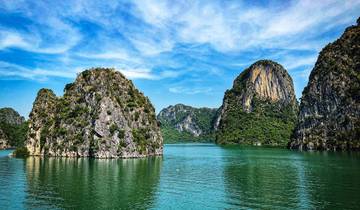Verdant water with towering limestone formations and clear blue skies.