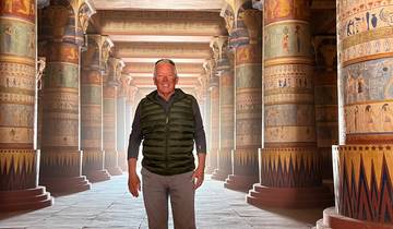Tourist standing in a temple with ornate columns.