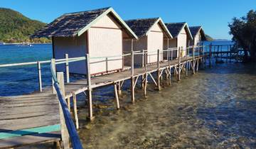 Rustic beach huts over clear, shallow water.