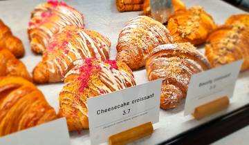 Display of various croissants in a bakery with price tags.