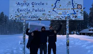 Three people at the Arctic Circle sign.