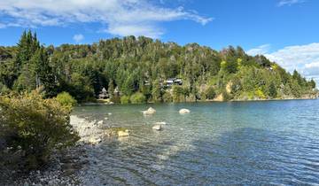 Clear lake surrounded by trees and rocky shore.
