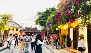 Bustling street in Hoi An with traditional lanterns and people walking.