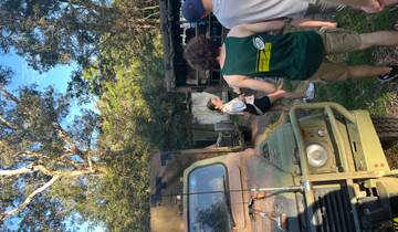 People exploring an outdoor area with military vehicles.