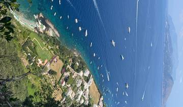 Aerial view of coastline with numerous boats on blue water.