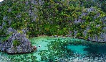 Aerial view of a tropical lagoon with turquoise waters and lush cliffs.