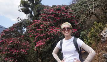 A woman posing with pink flowers on a hiking trail.
