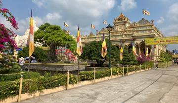 A vibrant temple with flags, plants, and visitors.