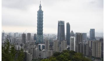 A city skyline with a tall tower amidst cloudy skies.