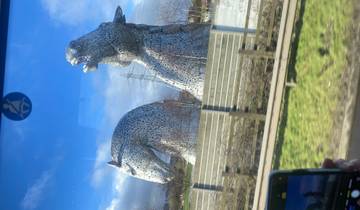 Large horse sculptures seen from a bus with people taking photos.