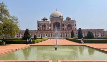 Historical mausoleum with a garden and fountain in front.