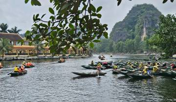 People rowing boats on a river surrounded by lush greenery and mountains.