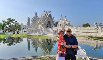Couple in front of a white temple with reflection in water.