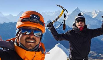 Two people in winter gear with ice axes on a snowy mountain with other mountains in the background.