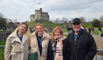 Group of people posing in front of a historic castle.