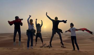 Group of people jumping in the desert at sunrise.
