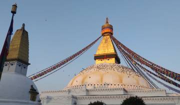 Boudhanath Stupa with prayer flags and a clear sky.