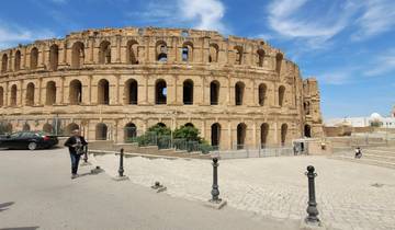 Colosseum-like structure with people walking nearby.