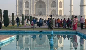 Visitors exploring the Taj Mahal with reflection in water.