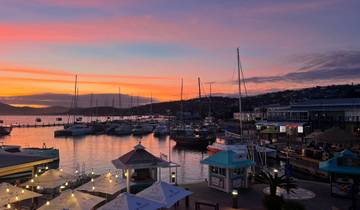 Sunset over a marina with sailboats and horizon view.