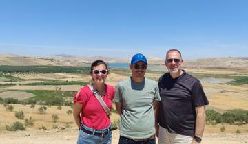 Three people posing in front of a picturesque landscape.