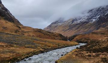 River flowing between rugged mountains with a glacier in the background.