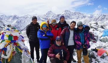 Group of people in colorful attire surrounded by mountains and snow.
