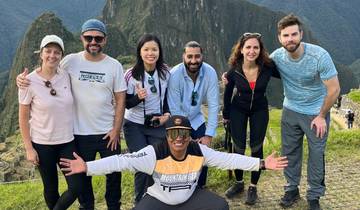 Group of hikers posing at a scenic overlook with mountains.