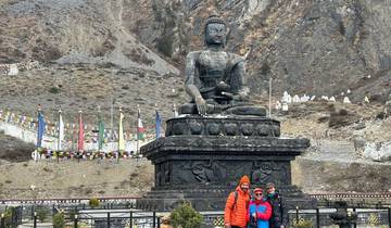 Tourists posing in front of a large Buddha statue.