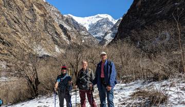 Three people trekking with a snowy mountain view.