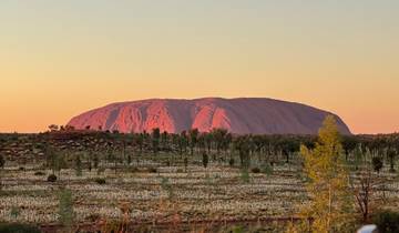 Sunset view of a famous rock formation surrounded by trees.