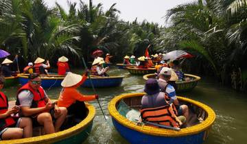 People rowing round boats in a lush canal.