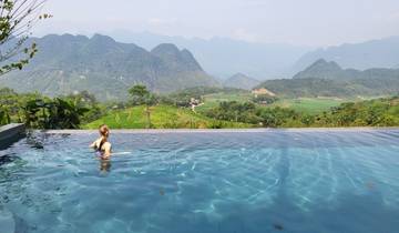 Person swimming in infinity pool with mountain view in the background.