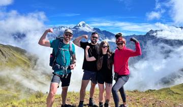 Four people flexing on a mountain top amidst clouds.