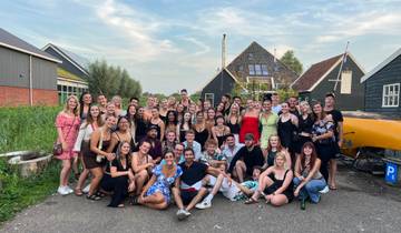 A large group of people posing outdoors with traditional Dutch houses.
