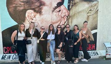 Group posing in front of a famous mural depicting a political scene.