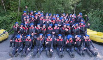 Group photo before rafting, wearing wetsuits and helmets.
