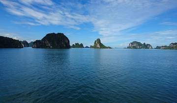Vast scenery of a bay with limestone islands under a bright blue sky.