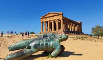 Ancient Greek temple with people and fallen statue in the foreground.